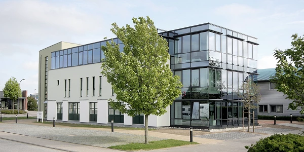 Modernes Bürogebäude mit Glasfassade und Baum im Vordergrund