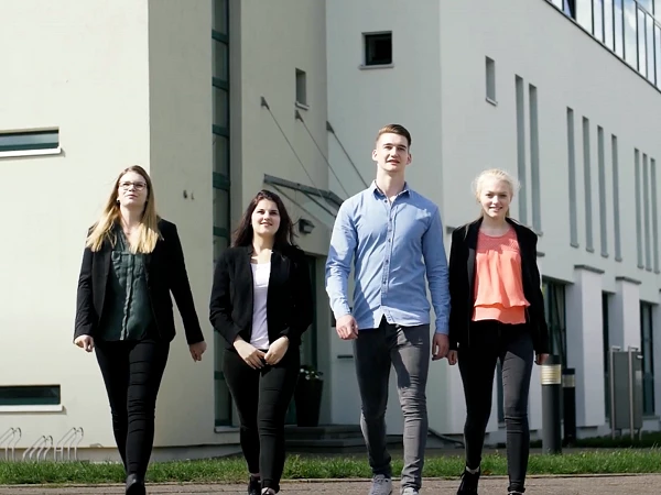 Vier junge Menschen laufen gemeinsam vor Bürogebäude