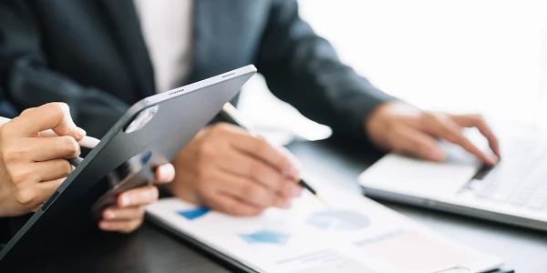 Zwei Personen analysieren Diagramme auf Tablet und Papier