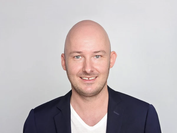 Porträt von Christoph Buck mit Glatze vor hellem Hintergrund